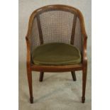 An Edwardian walnut and line inlaid library tub chair, with a caned back over a loose green cushion,