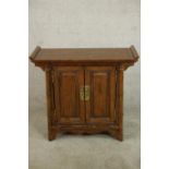 A late 20th century Chinese elm two door altar style cabinet with brass swing handles, the doors