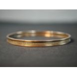 An antique 9ct rose gold bangle with beaded design around the middle with a rope design either side.