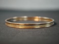 An antique 9ct rose gold bangle with beaded design around the middle with a rope design either side.