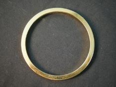 A contemporary 18ct yellow gold solid 0.5cm wide bangle. Hallmarked: BSP, London. Engraved to the