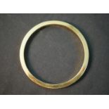 A contemporary 18ct yellow gold solid 0.5cm wide bangle. Hallmarked: BSP, London. Engraved to the