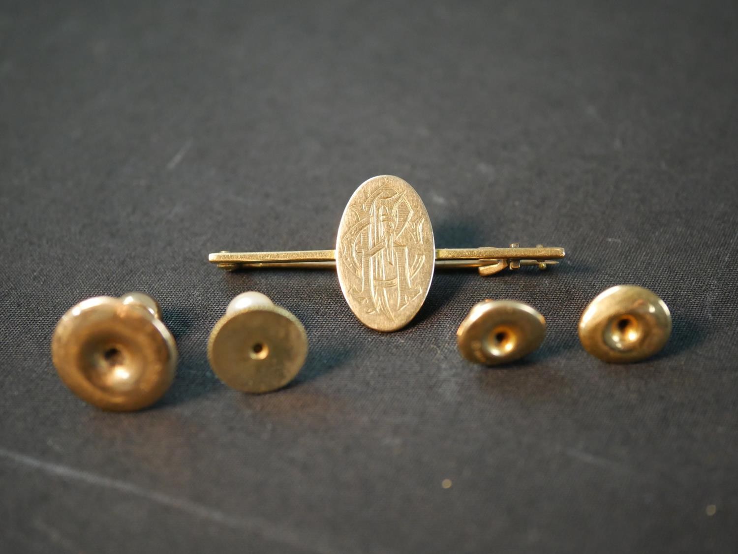 A yellow metal (tests as 9ct) engraved monogram bar brooch along with three 9ct shirt studs and a