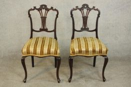 A pair of late Victorian carved walnut side chairs, the ornately carved back with a pierced splat,