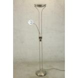 A brushed chrome floor standing uplighter lamp, with a reading lamp on an adjustable arm, on a