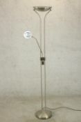 A brushed chrome floor standing uplighter lamp, with a reading lamp on an adjustable arm, on a