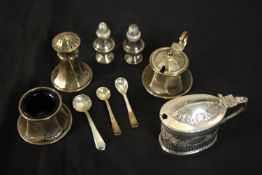 A collection of silver items, including a three piece cruet set, miniature pepper shakers and a