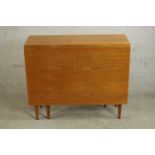A circa 1960s teak drop leaf dining table of rectangular form with two drop leaves on tapering