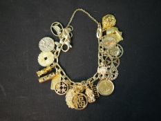 A 9ct curb link charm bracelet with twenty three yellow metal and mixed carat gold charms. The