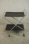 A circa 1970's tubular steel folding drinks trolley, with two black moulded tiers, on castors. H.