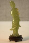 A carved Chinese jade figure of Guanyin on a carved hardwood base. (Some damage as seen). H.20 W.7