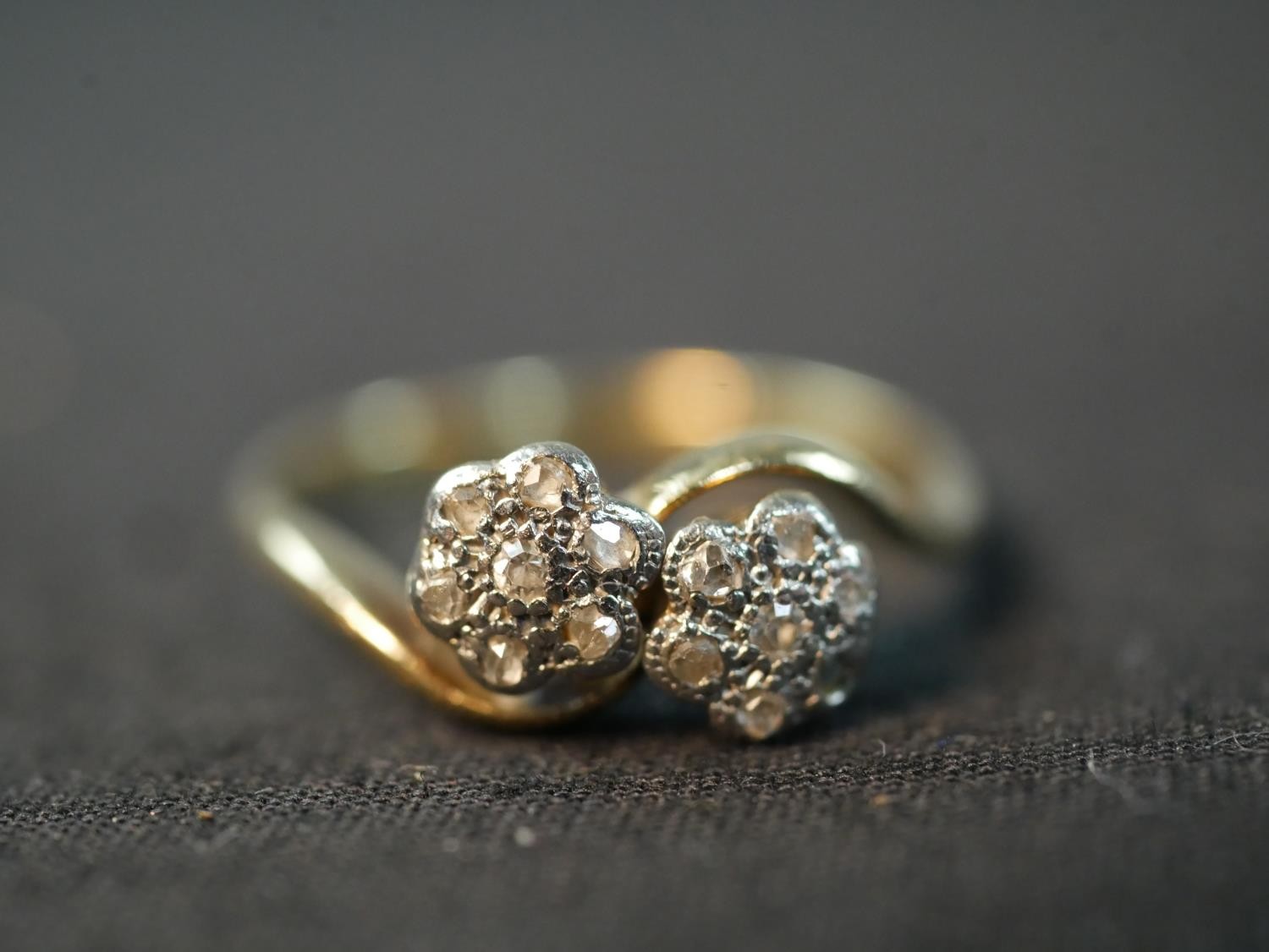 An Edwardian yellow metal (tests higher than 9ct) and rose cut diamond floral cross over ring,
