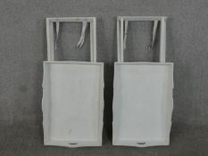 A pair of contemporary light grey painted butlers stands, the trays with pierced handles, on folding