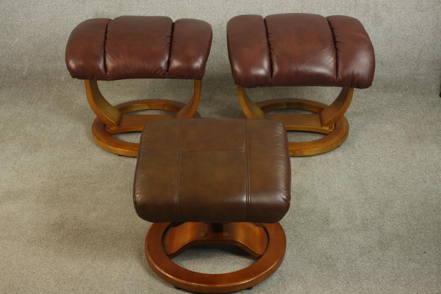 Three late 20th century Stressless style foot stools, inluding a pair upholstered in burgundy