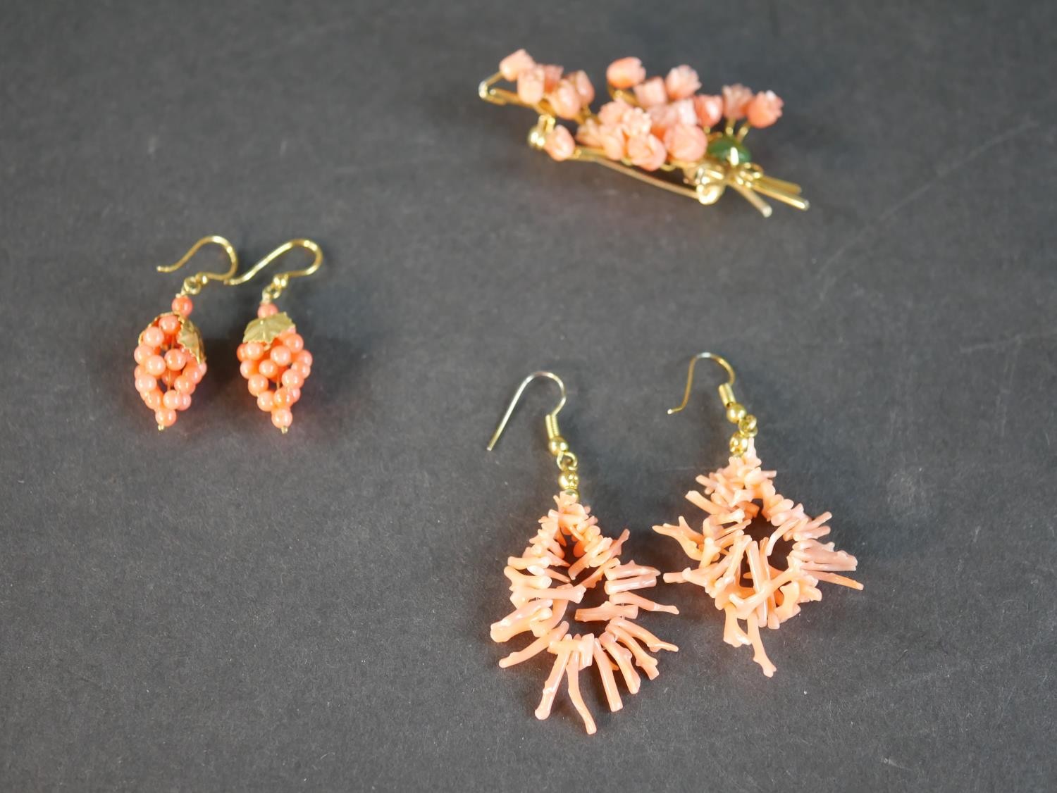 A collection of coral jewellery, including a pair of coral bead grape earrings with gilded leaves, a