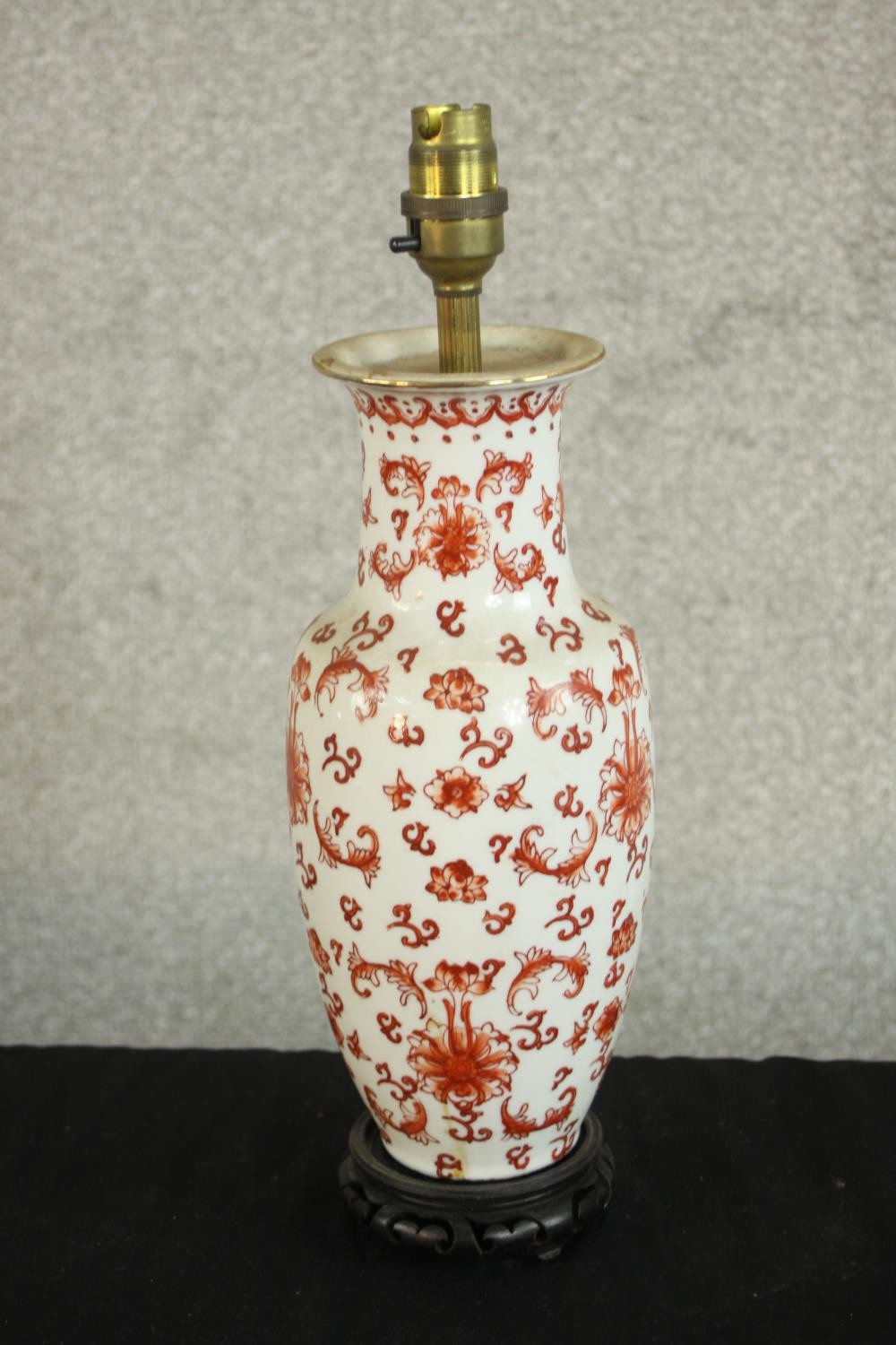 A late 20th century Chinese porcelain table lamp, enamelled with various designs in red, on a carved