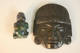 A carved green hardstone Mayan/Aztec mask along with a stone figure of a man. H.18 W.14cm. (largest)