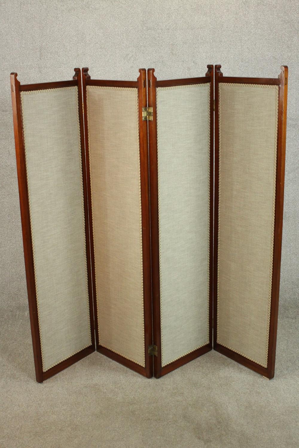 An Edwardian walnut fourfold screen, each panel upholstered with an oatmeal coloured fabric, with