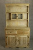 A 20th century pine dresser, the upper section with two shelves incorporating a pair of leaded glass