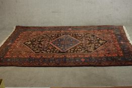 A hand made red ground Persian Hamadan carpet with central lozenge medallion within stylised