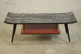 A 1950s coffee table, the laminated top with raised ends, supporting a red undertier, on splayed