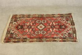 A hand woven red Persian Hamadan with central medallion on burgundy ground within spandrels and
