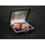 A pair of 14 carat yellow gold Tugtupite cabochon set cufflinks with hinged torpedo fittings.
