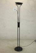 A contemporary black floor standing uplighter lamp, with a reading lamp on an adjustable arm, on a