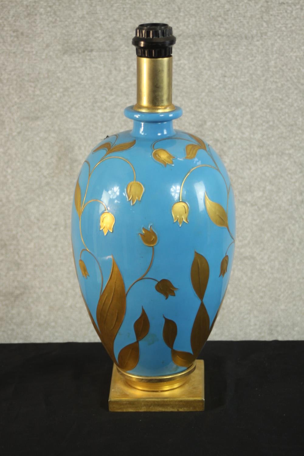 A contemporary gilded and blue opaque glass painted table lamp, of ovoid form and on a square gilt