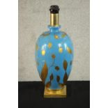 A contemporary gilded and blue opaque glass painted table lamp, of ovoid form and on a square gilt