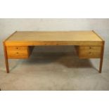 A circa 1970's Danish design inspired teak executive desk, the rectangular top over two pairs of