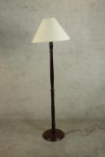 A 20th century mahogany standard lamp, with a turned stem and circular base and white shade. H.154