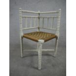 A late 19th century white painted corner chair, with a woven seat, on bobbin turned and