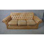 A Thomas Lloyd sofa in deep buttoned leather upholstery and the matching footstool. H.73 W.197 D.