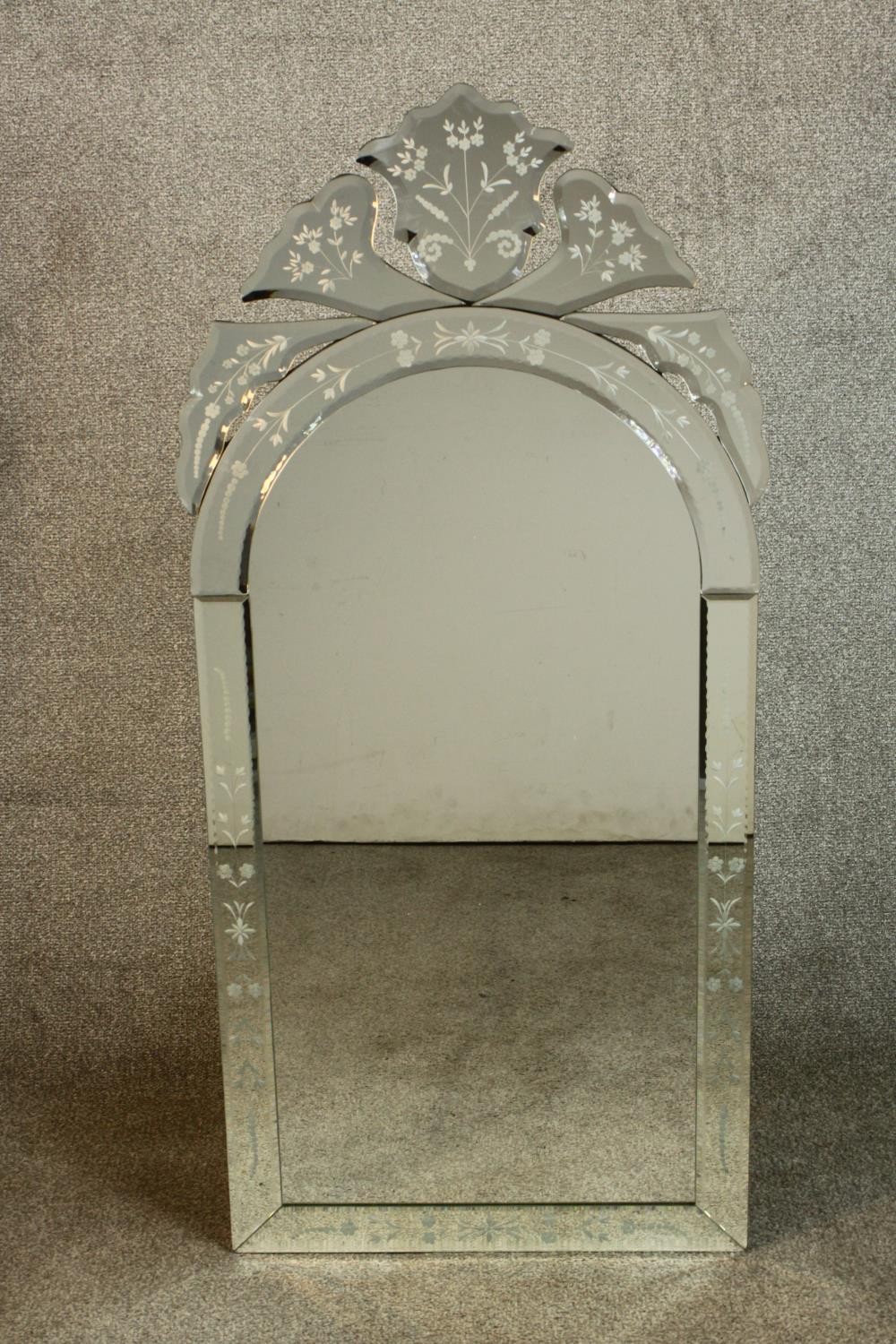 A contemporary Venetian style wall mirror with a shaped bevelled mirror plate within etched