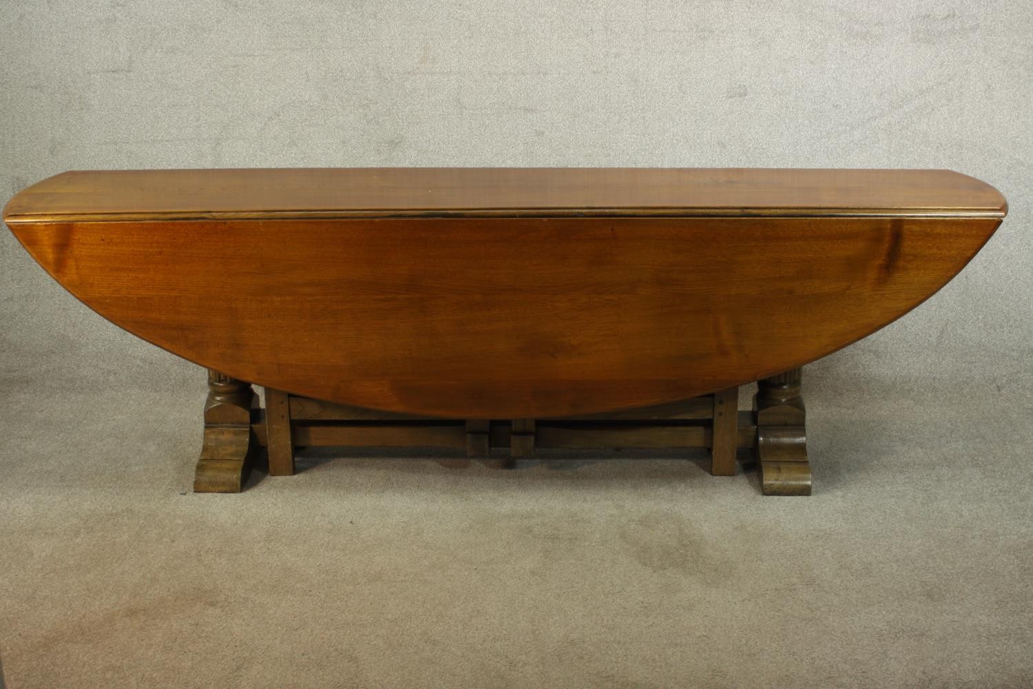 A 20th century oak drop leaf wake table, the oval top with two drop leaves raised on gate legs and
