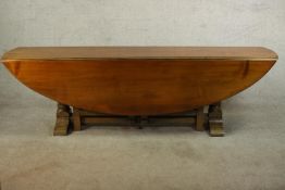 A 20th century oak drop leaf wake table, the oval top with two drop leaves raised on gate legs and