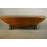 A 20th century oak drop leaf wake table, the oval top with two drop leaves raised on gate legs and