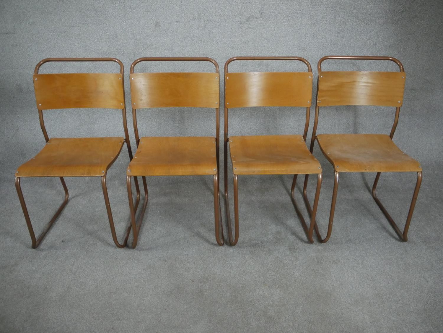 A set of four 1950s Redro plywood stacking school chairs, on brown painted tubular frames. H.84 W.44