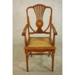 An early 20th century walnut and marquetry inlaid armchair, with a pierced splat back over a caned