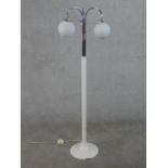 An Art Deco white enamelled chrome three branch standard lamp with two opaque white glass globe