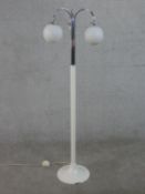 An Art Deco white enamelled chrome three branch standard lamp with two opaque white glass globe
