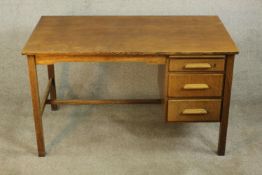A circa 1940's oak utility desk, the rectangular top over a kneehole and a bank of three short