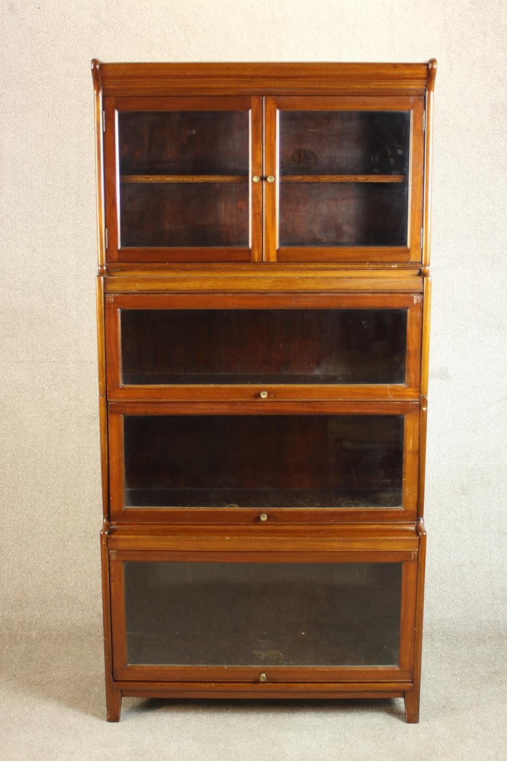 A mid 20th century mahogany Gumm stacking bookcase, with two glazed cupboard doors over three