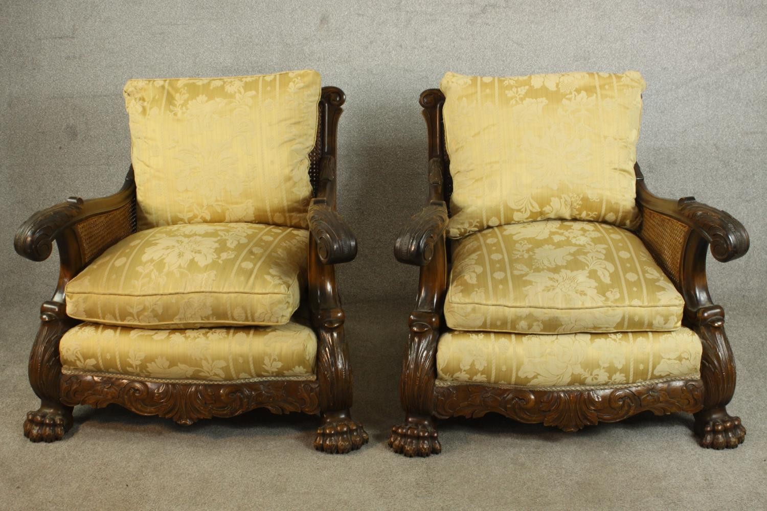 A pair of early 20th century Continental carved walnut bergere armchairs, upholstered in gold