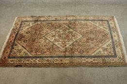 A hand made Persian Hamadan rug with central floral medallion on a biscuit ground within foliate