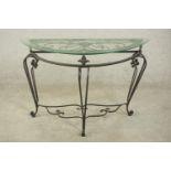 A contemporary wrought iron side table, of demi lune form with a plate glass top on three