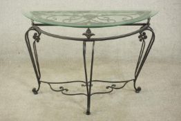 A contemporary wrought iron side table, of demi lune form with a plate glass top on three