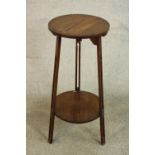 An Arts & Crafts oak lamp table, with a circular top on three pierced legs joined by a circular