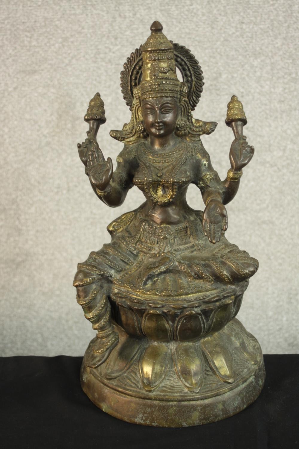 An early 20th century brass figure of the Indian deity Lakshmi on a lotus form base. (Damaged.) H.43